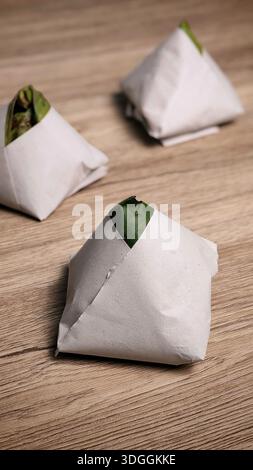 Traditionelle Packungen von Nasi-Lemak in Bananenblatt und Papier auf Holztischhintergrund gewickelt Stockfoto