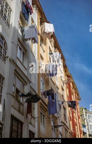 Wäscherei hängt zum Trocknen auf Wäscheleinen zwischen alten Wohngebäuden in Santander, Spanien. Ein Konzept des traditionellen Alltags, der Gemeinschaft und des Alltags Stockfoto