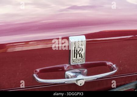 Malmö, Schweden - 7. August 2025: In einer Nahaufnahme werden die Verzierung und der Griff der Motorhaube eines klassischen Rolls Royce-Autos aufgenommen, die das Fahrzeug in kastanienbraunen Farben hervorheben Stockfoto