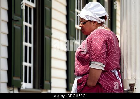 Frau in zeitgenössischer Kleidung, die sich ein Gebäude in Colonial Williamsburg ansieht, ein Eindruck aus der Kolonialzeit, Williamsburg, Virginia, USA Stockfoto
