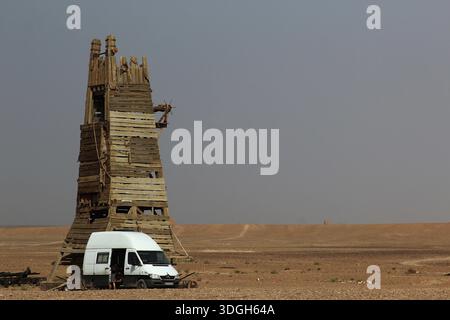Wüstenszene mit einem hohen rustikalen Turm und einem Minibus im Vordergrund, Ouarzazate, Marokko Stockfoto