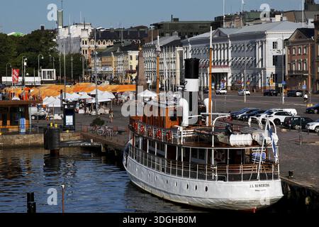 Der Marktplatz in Helsinki mit einem Boot und historischen Gebäuden entlang der belebten Hafenpromenade, Helsinki, Finnland Stockfoto