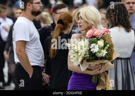 Blonde Frau mit einem Blumenstrauß während einer Abschlussfeier auf einem geschäftigen Platz in Vilnius, Bezirk Vilnius, Litauen Stockfoto