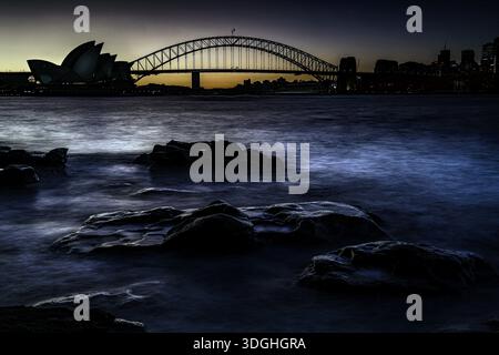 Silhouette des Opernhauses von Sydney und der Harbour Bridge in der Abenddämmerung, Sydney, New South Wales, Australien Stockfoto
