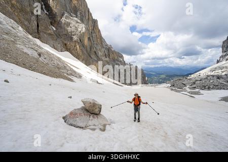 Bergsteiger auf einem Schneefeld, Führer zum Rifugio Brentei auf einem Felsen, Überreste des Gletschers Vedretta dei Camosci, Brenta-Berge, Brenta-Adamello Natura Stockfoto