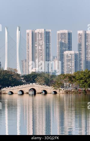 Traditionelle Steinbrücke über den See mit moderner Skyline im Hintergrund - Westsee in Huizhou, Provinz Guangdong, China, ist eine Touristenattraktion mit antiker Architektur Stockfoto