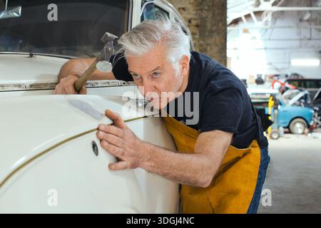 Ein Spezialist für Autoreparatur führt akribisch Paneele und Metallrestaurierungen durch. Stockfoto