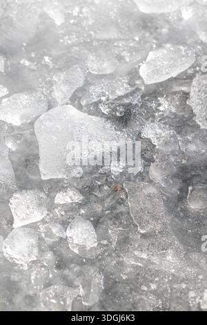 Nahaufnahme-abstrakte Textur gebrochener, schmelzender Eisstücke. Sonnenlicht scheint durch die halbtransparenten Fragmente und zeigt die komplizierten Details von f Stockfoto
