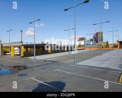 Das leere Dachgeschoss eines modernen Parkhauses mit dem Kiewer Fernsehturm im Hintergrund. Diese urbane Landschaft unterstreicht die moderne Infrastruktur Stockfoto