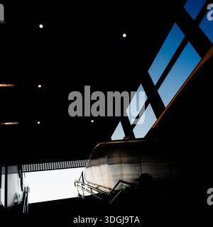 Abstrakte architektonische Komposition mit tiefschwarzen Schatten und hellblauem Himmel, sichtbar durch eine geometrische Dachkonstruktion. Die kontrastreiche Krea Stockfoto