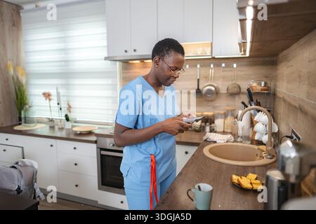 Krankenschwester mit Smartphone in der Küche in der Pause Stockfoto