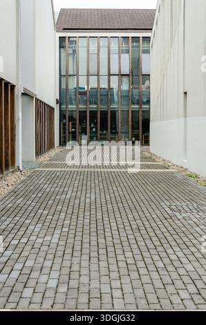 HANGZHOU, CHINA - 6. JULI 2017: Eine enge gepflasterte Gasse oder ein Innenhof zwischen modernen Gebäuden mit Glasfassaden im Kulturdorf Liangzhu. Stockfoto