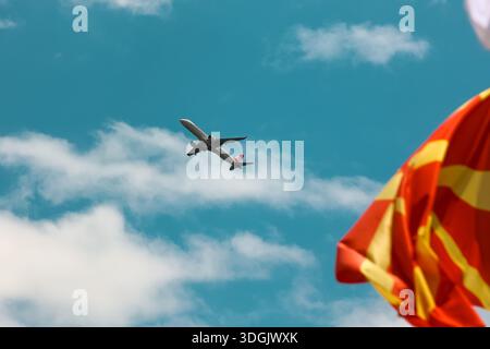 Passagierflugzeug fliegt über mazedonischer Flagge gegen blauen Himmel Stockfoto