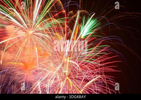 Buntes Feuerwerk explodiert am dunklen Nachthimmel während einer Feiertagsfeier und schafft eine magische Atmosphäre der Freude und des Glücks für Silvester Stockfoto