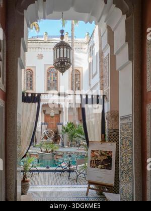Innenraum eines traditionellen Morroc Riads mit einem kleinen Brunnen in der Mitte, Blick vom Türweg, Fès, Morroco Stockfoto