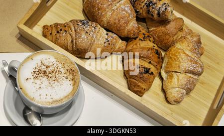 Köstliche Croissants und Kaffee auf einem Holztablett Stockfoto