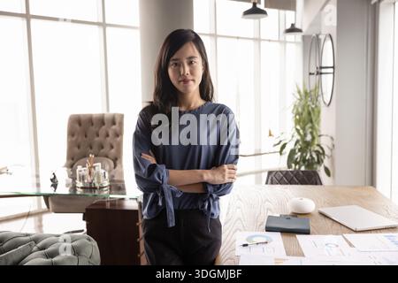 Selbstbewusste junge asiatische Marketinganalytikerin, die im Amt steht Stockfoto