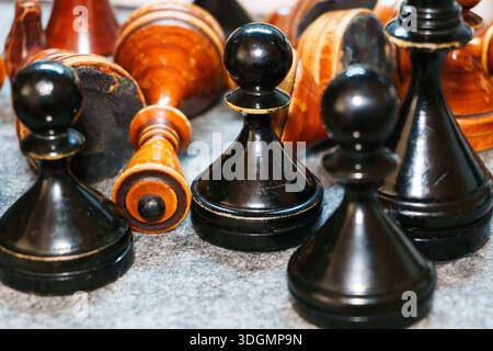 Alte Schachfiguren, schwarz oder braun, aus Holz, eine schwarze Schachfigur unter weißen Stücken, verschiedene und besondere, schwarze Moves zuerst, Siegerspiel, Schachturnier Stockfoto