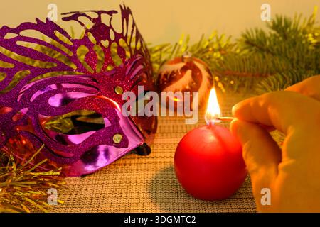 Handzünder einer Kerze vor dem Hintergrund der Weihnachtsdekoration. Weihnachts- und Neujahrskonzept. Stockfoto