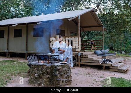 Ein Paar entspannt sich bei einem gemütlichen Kamin, grillen und gemeinsame Momente in der ruhigen Umgebung der Panorama Route, Südafrika. Dieses friedliche Hotel Stockfoto