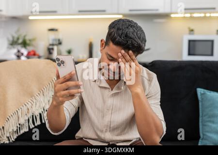 Der indische Mann zu Hause spielt die mobile Spielrunde verliert die Facepalm verärgert und ist bereit für das Rückspiel. Arabian Guy auf Sofa Tips versuchen Sie es erneut auf Smartphone Pläne Comeback konzentriert sich auf die nächste Stufe und die Wiederherstellung der Punktzahl Stockfoto