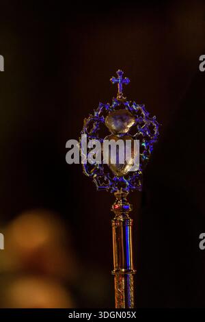 Ein wunderschön gestaltetes Personal mit Herzformen und einem Kreuz leuchtet sanft in einer schwach beleuchteten Umgebung und zeigt seine Details. Stockfoto