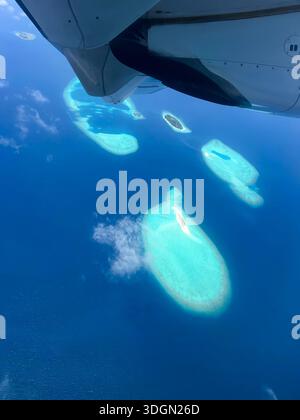 Ein Flugzeug fliegt über den Ozean und das Wasser ist blau. Es gibt Inseln im Wasser Stockfoto