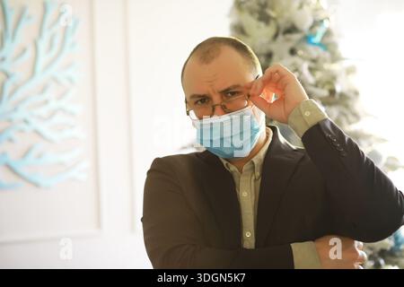 Ein Mann in einer medizinischen Maske hält eine Packung hundert Dollar Scheine in den Händen. Das Wirtschaftswachstum. Stockfoto