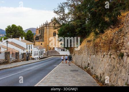 Blick auf die Kirche der Festung Heiliger Geist mit Fußgängern und traditionellen weißen Häusern. Gotische und Renaissance-Architektur in Ronda, Malaga. Stockfoto