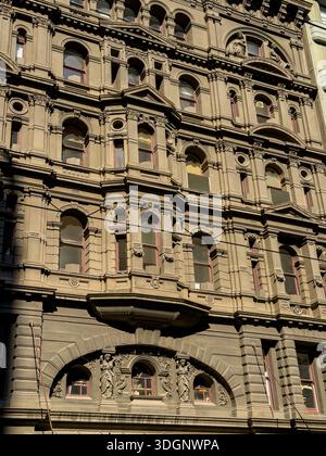 Die kunstvoll verzierte, mehrstöckige Gebäudefassade zeigt detaillierte Steinschnitzereien, bogenförmige Fenster mit roten Rahmen und klassische architektonische Elemente in Sonnenschein Stockfoto