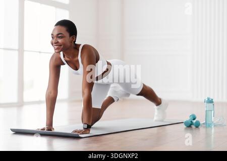 Afro-Fröhliche Frau, Die Die Übung Von Cross Body Mountain Kletterern Macht Stockfoto