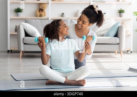 Liebevolle afroamerikanische Mutter und Tochter mit Langhanteln Stockfoto