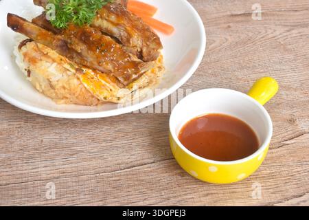 Gegrilltes Schweinerippensauce mit Spiegelrahm-Ei-Omelett auf Reis mit gekochter Karotte auf Teller Stockfoto