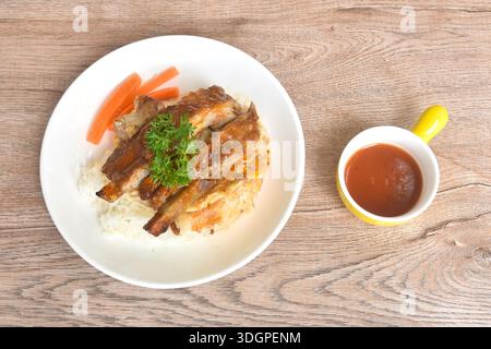 Gegrilltes Schweinerippensauce mit Spiegelrahm-Ei-Omelett auf Reis mit gekochter Karotte auf Teller Stockfoto