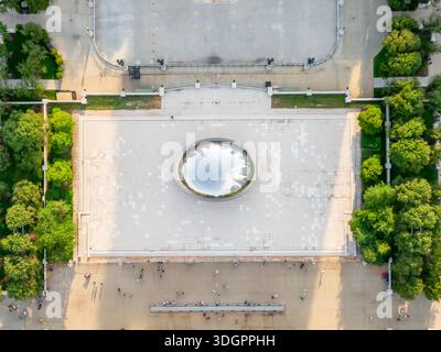 Ein Blick aus der Vogelperspektive auf Cloud Gate („The Bean“) zeigt seine reflektierende, nahtlose Oberfläche, die Chicagos Skyline und Wolken im Millennium Park widerspiegelt. Besucher gehen um die berühmte, bogenförmige Skulptur herum. Stockfoto