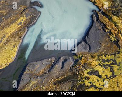 Ein abstrakter Blick von oben auf das türkisfarbene Schmelzwasser, das entlang des mäandernden Flussverbands unterhalb der Solheimajokull Glacier Lagune fließt Stockfoto