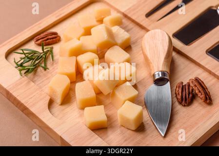 Gewürfelter Cheddar, Gouda oder Parmesankäse auf einem Schneidebrett. Gewürfelter Käse als Lebensmittelhintergrund für Ihr Design Stockfoto