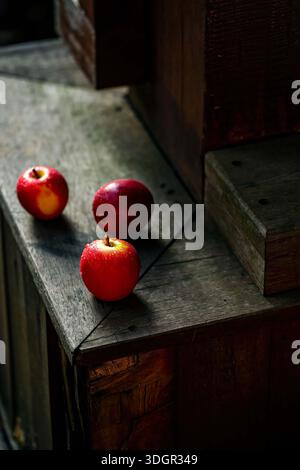 Drei frische rote Äpfel mit Wassertropfen auf dunklem Vintage-Holzhintergrund Stockfoto