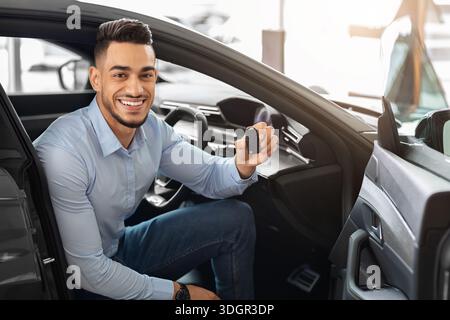 Hübscher arabischer Mann, der im Auto sitzt und den Schlüssel hält Stockfoto