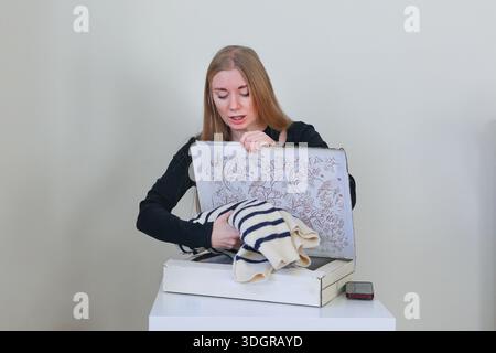 Junge Frau, die verkaufte Kleidungsstücke für den Versand verpackt erfolgreiche Online-Marktplattentransaktion Stockfoto