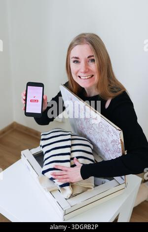 Online Second Hand Sale Konzept Frau verpackt Kleidung nach erfolgreicher mobiler Transaktion Stockfoto