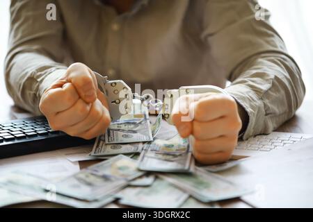 Hände eines Betrügers mit Handschellen auf dem Hintergrund von uns Dollars und Kreditkarten. Betrug, Cyberkriminalität. Kreditkartenbetrug. Verhaftung eines Enterp Stockfoto