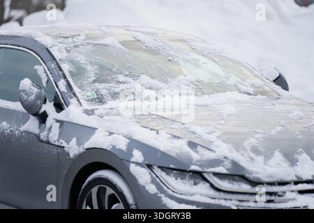 Gefrorene Windschutzscheibe und Schnee auf der Motorhaube eines modernen Autos, Nahsicht auf Winterkarosserie und Glas mit Eiskruste, saisonales Fahrsicherheitskonzept Stockfoto
