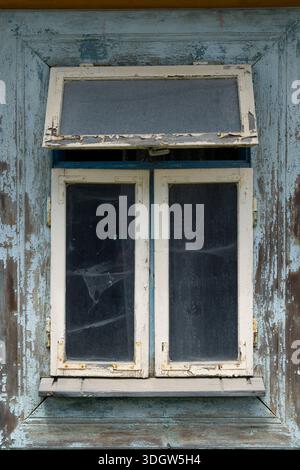 Das Holzfenster mit abblätternder blauer Farbe zeigt Verfall und rustikale Textur Stockfoto