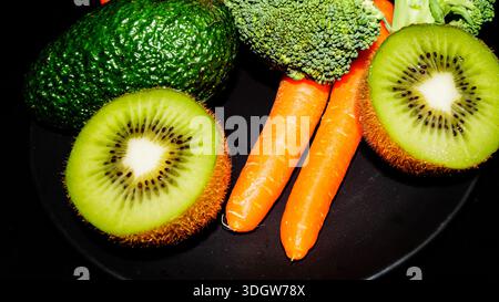 Auswahl an frischem Bio-Gemüse und Obst einschließlich Avocado Kiwi Brokkoli und Karotten für einen gesunden Lebensstil. Stockfoto
