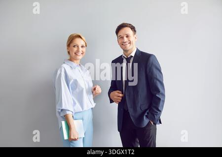 Geschäftsleute stehen isoliert auf grauem Hintergrund und schauen in die Kamera. Stockfoto