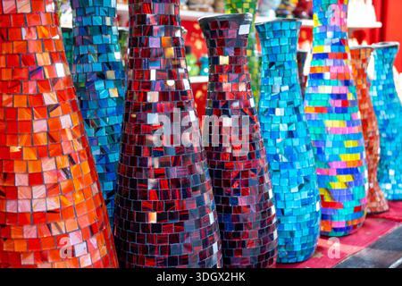 Farbige Glasvasen mit rotem, blauem und mehrfarbigem Mosaik. Kunstausstellung auf dem Weihnachtsmarkt. Handgefertigte Vase für den Innenraum. Stockfoto
