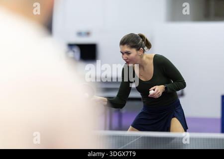 Junge Frau, die Tischtennis spielt, konzentriert sich auf das Spiel Stockfoto