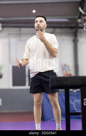 Männlicher Athlet hüpft Tischtennisball und bereitet Servieren vor Stockfoto