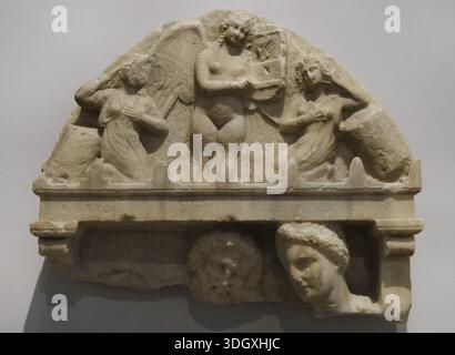 Das Antike Griechenland. Krönung der Grabstele von Proxenides, aus dem Demé von Steiria (Attika, Griechenland), seiner Frau Aristodike und Menippe. Zwei professionelle Trauerfrauen stellen die Sirene ein, die Kythara spielt. Unten ein männlicher und ein weiblicher Kopf. Aus Piräus, 350-330 v. Chr. Archäologisches Museum von Piräus. Griechenland. Stockfoto